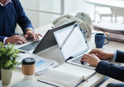 Cropped image of business people working on laptops in office